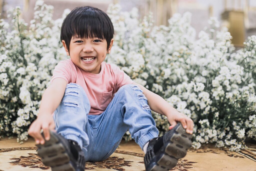 Kind auf dem Boden vor einer Blumenwiese